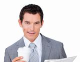 Male executive holding a drinking cup and reading a newspaper 