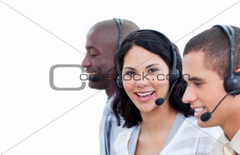 Portrait of a brunette woman and her team working in a call cent
