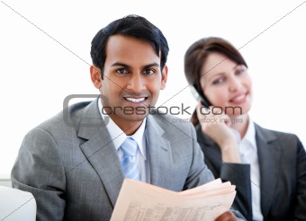 Smiling businessman reading a newspaper in a waiting room