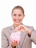 Assertive businesswoman saving money in a piggybank
