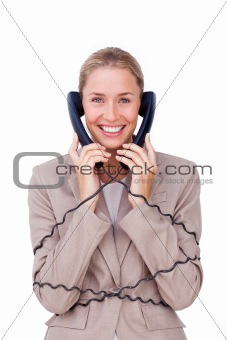Smiling businesswoman tangled up in phone wires 