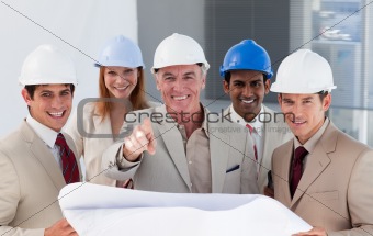 A group of smiling architects studying blueprints