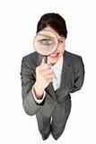 Young businesswoman looking through magnifying glass 