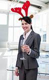 Smiling businesswoman with a novelty Christmas hat toasting with