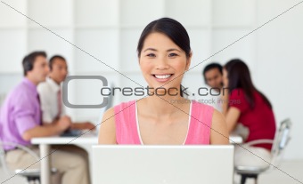 Smiling asian businesswoman at her computer