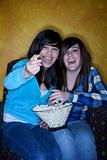 Pretty Hispanic girls with popcorn watching television