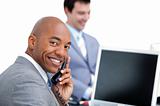 Happy businessman on phone and his colleague working at a comput