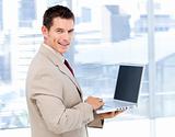 Positive businessman using a laptop standing 