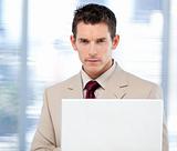 Self-assured businessman using a laptop standing
