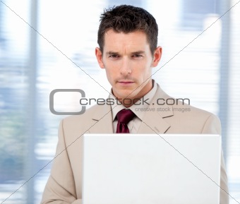 Self-assured businessman using a laptop standing