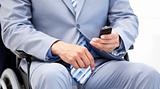 Close-up of a businessman sitting on a wheelchair sending a text