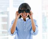 Positive female executive looking through binoculars