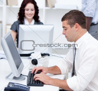 Assertive young business people working at computers