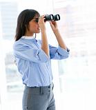 Confident female executive looking through binoculars