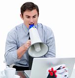 Angry businessman yelling through a megaphone sitting at his des