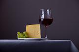 piece of cheese,a bunch of grapes and red wine