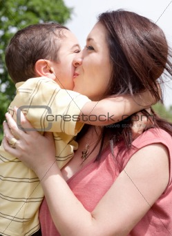 Children kissing his mom in the park