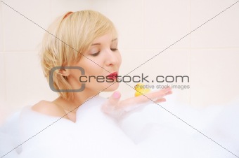 Smiling blond woman lying in bubble bath