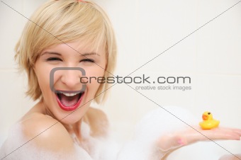 Smiling blond woman lying in bubble bath