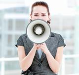 Angry businesswoman yelling through a megaphone