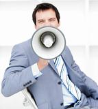 Furious young businessman yelling through a megaphone