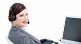 Confident businesswoman with headset on sitting at her desk 