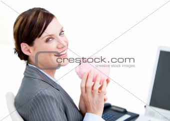 Cheerful businesswoman holding a piggy-bank