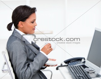 Attractive businesswoman drinking a coffe while working at a com
