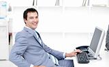 Smiling young businessman working at a computer 