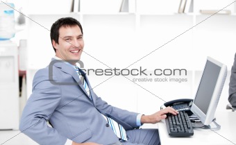 Smiling young businessman working at a computer 