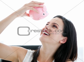 Cute businesswoman looking at a piggybank 