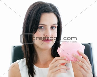 Beautiful businesswoman holding a piggybank and looking at the c