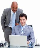 Ethnic manager assisting his colleague at a computer