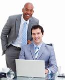 Smiling manager assisting his colleague at a computer