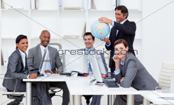 Smiling manager holding a globe with his team working at compute
