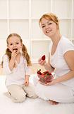 Woman and little girl eating fresh strawberries