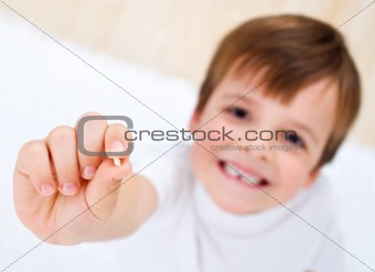 Little boy showing his milk-tooth in his hand
