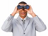 Serious young businessman looking through binoculars 