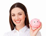 Smiling businesswoman saving money in a piggybank in the office