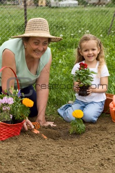 Grandmother teaching little girl gardening