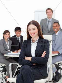 Smiling businesswoman sitting in front of her team 