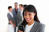 Smiling businesswoman sending a text in front of her team 