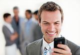Attractive businessman sending a text in front of his team 