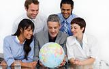 Smiling business people looking at a terrestrial globe 
