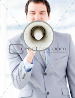 Portrait of a stressed businessman using a megaphone in the office