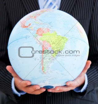 Close-up of a relaxed businessman holding a globe