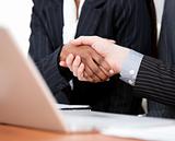 Close-up of a handshake between two businessmen with laptop