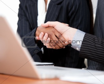 Close-up of a handshake between two businessmen with laptop