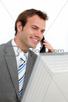 Charming businessman on phone at a computer 