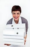 Smiling businesswoman putting a stack of folders on a desk 